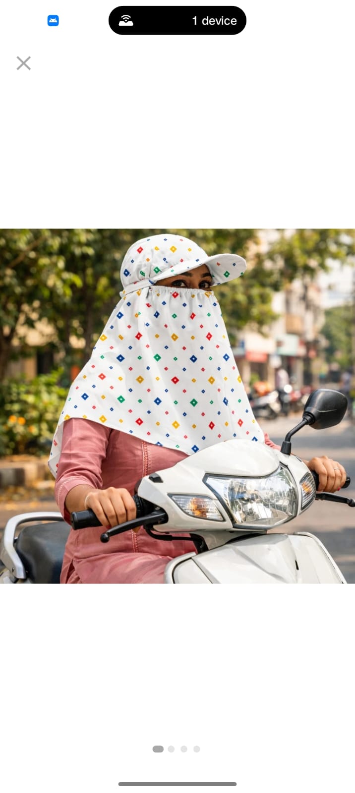 Woman wearing a polka dot scarf cap while riding a scooter